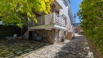 Un patio empedrado con un edificio de dos pisos, mobiliario exterior y una bicicleta.