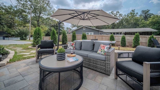 A patio with outdoor furniture, a round table, and a large umbrella.
