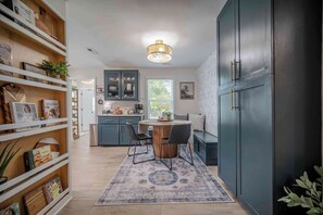 A modern kitchen with a dining area, wooden shelves with books, and a large cabinet. - Walk to Downtown Acworth | Patio | Fire Pit (Acworth)