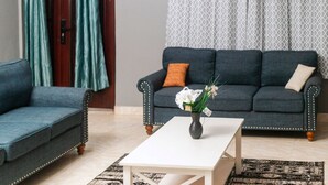 A living room with a dark blue sofa, a white coffee table, and a patterned rug.