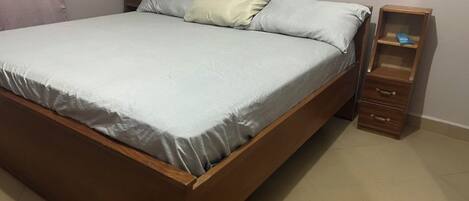 A bedroom with a wooden bed, a nightstand, and a small wooden cabinet.