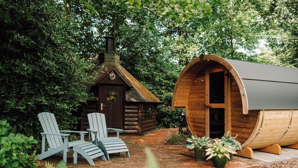A wooden cabin with a chimney, a log cabin, and a wooden barrel house. There are two Adirondack chairs outside. - Cozy vacation homes and apartments - here you will find peace and relaxation (Emstek)