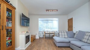 A living room with a sofa, a television, a cabinet, and a fireplace. - Spacious 3BDR Home with Workspace in Prime Spot (Greater London)
