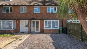 A two-story brick house with a tiled roof, a front door, and a small front yard with gravel. - Spacious 3BDR Home with Workspace in Prime Spot (Greater London)