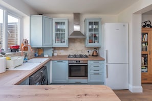 A kitchen with light blue cabinets, a Bosch refrigerator, a gas stove, and a dishwasher. - Spacious 3BDR Home with Workspace in Prime Spot (Greater London)