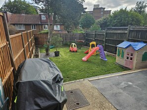 A backyard with a playset, a covered grill, and a small house. - Spacious 3BDR Home with Workspace in Prime Spot (Greater London)