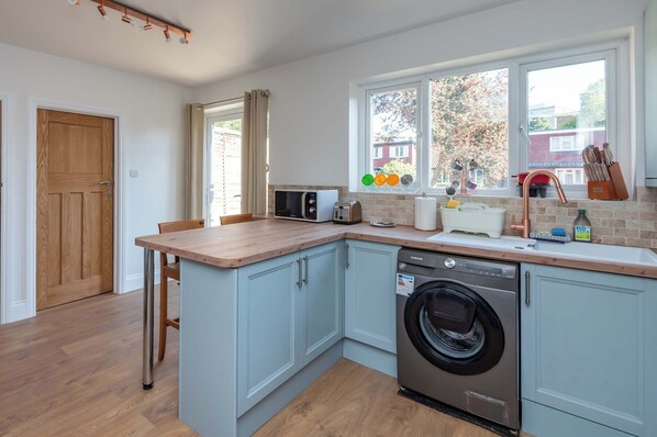 A compact kitchen with a washing machine, a microwave, and a toaster.