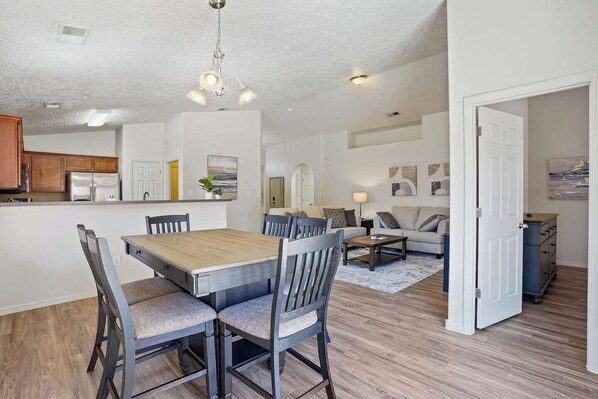 A spacious living area with a dining table, chairs, a sofa, and a coffee table.