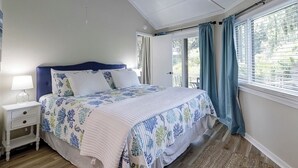 Un dormitorio con cama, mesita de noche y ventana con cortinas.