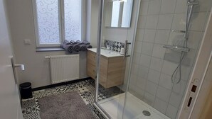 A bathroom with a shower, a window, patterned floor tiles, and a towel rack. - B As in... Forest walk (Saint-Amand-les-Eaux)
