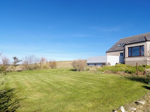 A modern house with a well-maintained lawn and a clear blue sky.