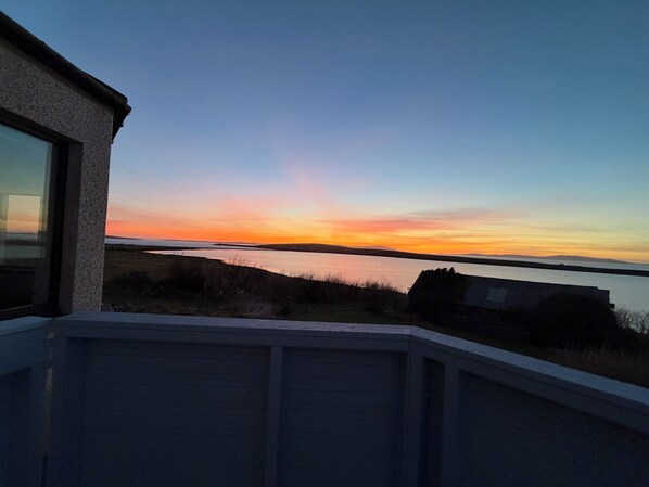 Vista desde un balcón sobre un cuerpo de agua al atardecer.