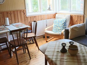 Ein gemütliches Zimmer mit Esstisch, Stühlen, einer Couch und einem Fenster mit Jalousien.