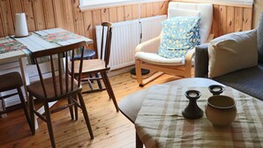 Una habitación acogedora con una mesa de madera, sillas, un sofá y una ventana con persianas.