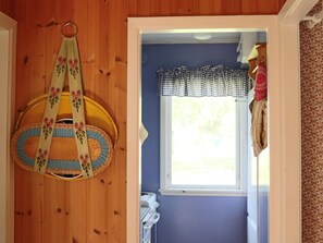 A room with a wooden wall, a hanging bag with a floral pattern, a window with a checkered valance, and a door leading to another room. - 4 Person Holiday Home in Skummeslovsstrand (Skummesloevsstrand)