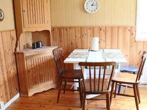 Un coin repas en bois avec une table, des chaises et une horloge au mur.