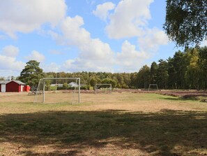 Ein Sportplatz im Freien mit Torpfosten und einem roten Gebäude im Hintergrund.