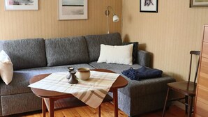 Una sala de estar con un sofá gris, una mesita con un cuenco y velas, y una lámpara en la pared.