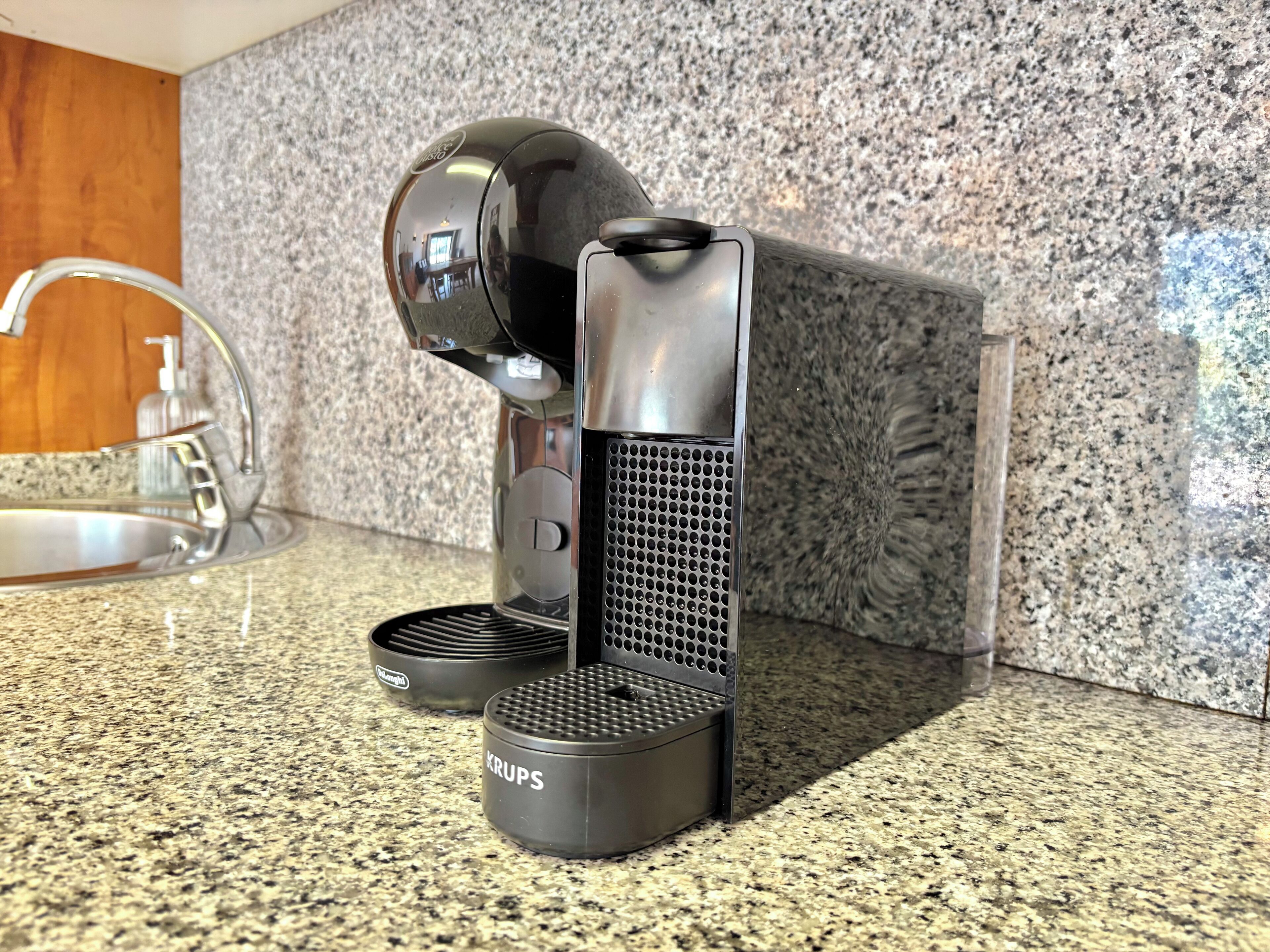 A coffee machine with a Krups brand kettle and a water reservoir on a granite countertop.