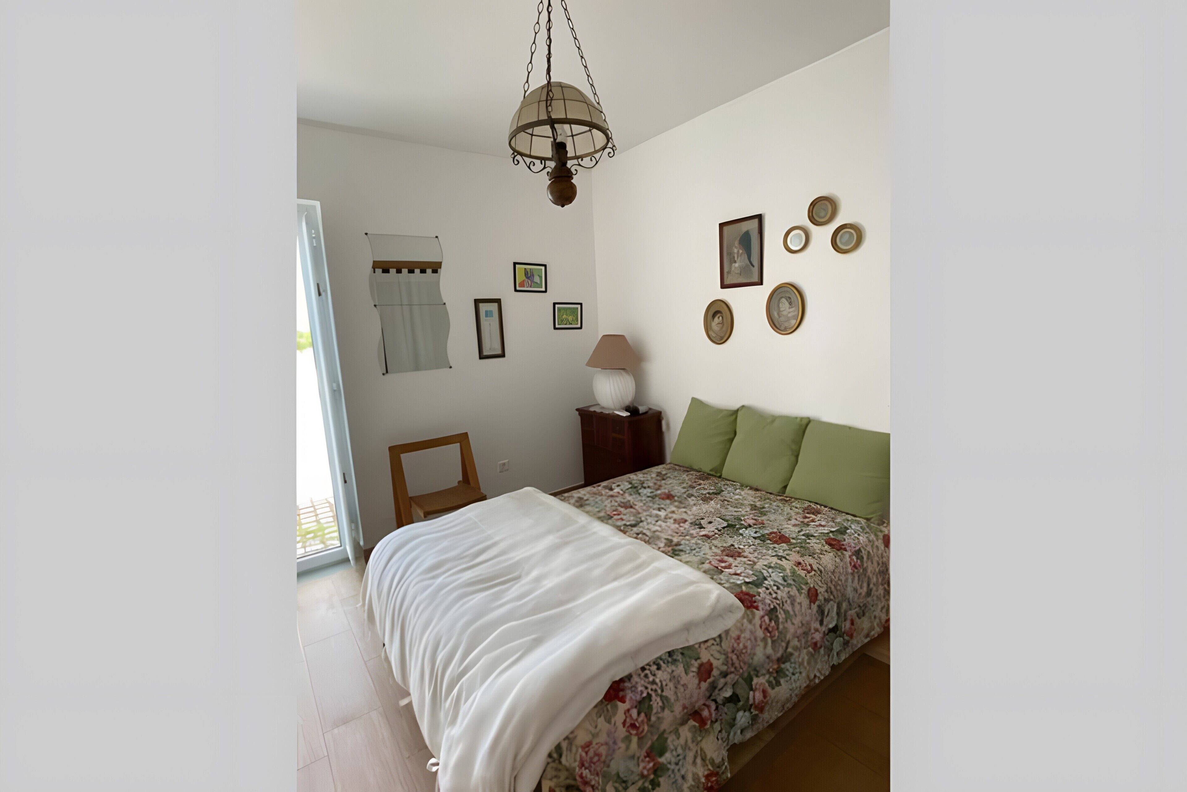 Een slaapkamer met een bed, een stoel, een lamp en decoraties aan de muur.