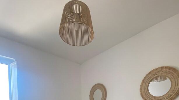 Une chambre d’hôtel avec deux lits, une grande fenêtre, un luminaire suspendu et un miroir fixé au mur.
