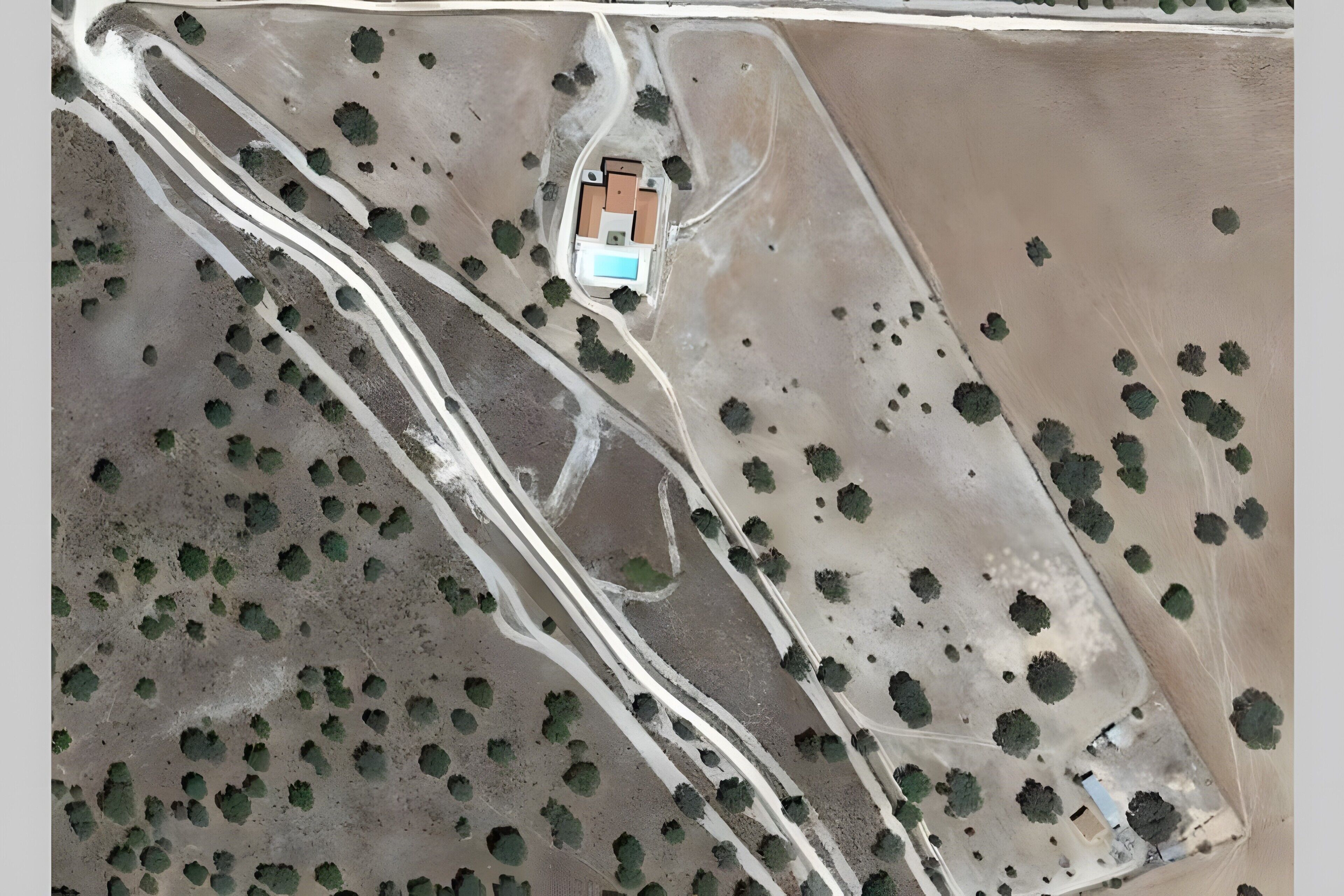 Une vue aérienne d’une propriété comprenant un bâtiment central, entouré de routes et parsemé d’arbres.