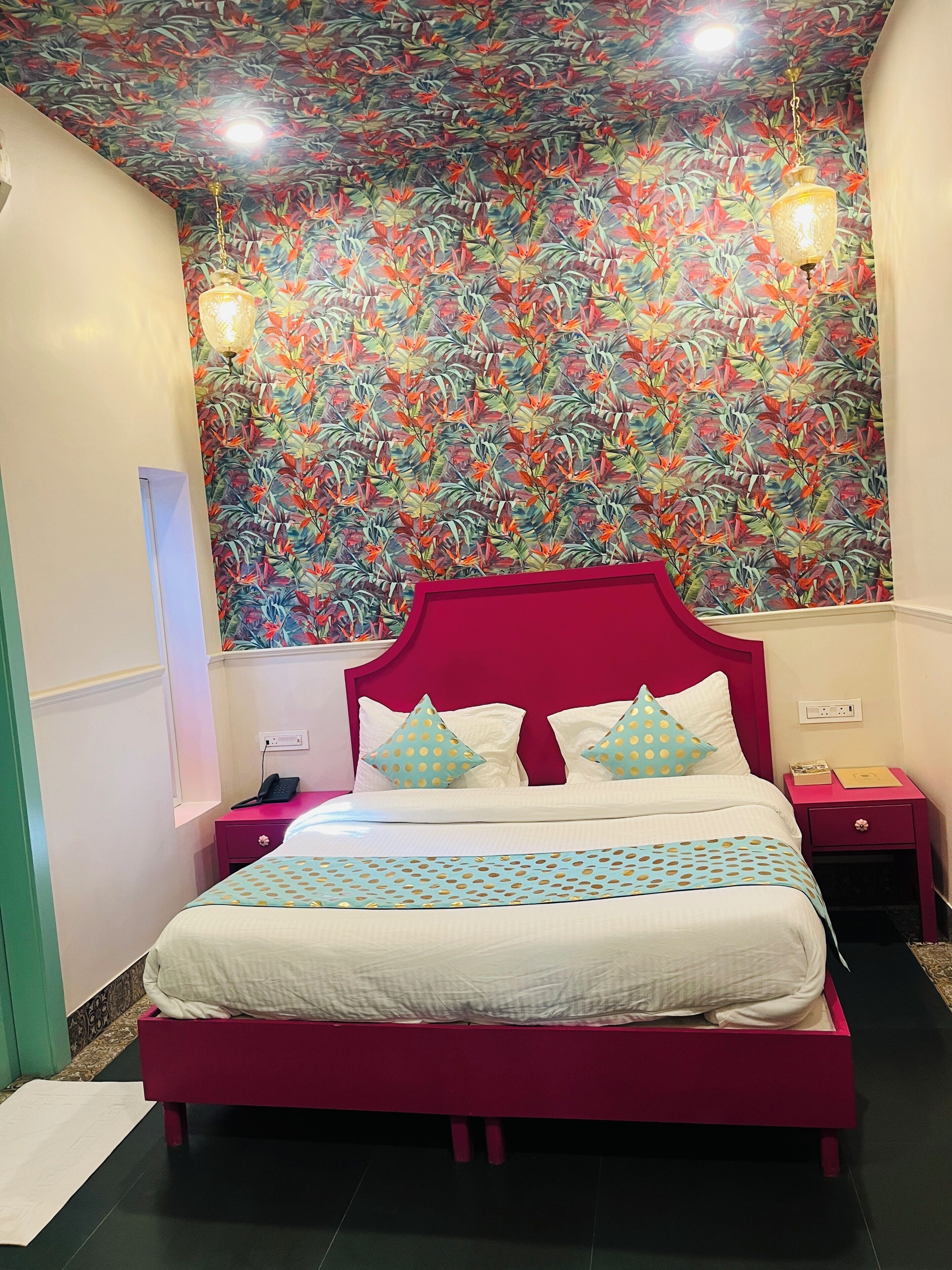 A bed with a red headboard, white bedding, and polka dot pillows. There are two bedside tables with lamps and a wall-mounted phone.