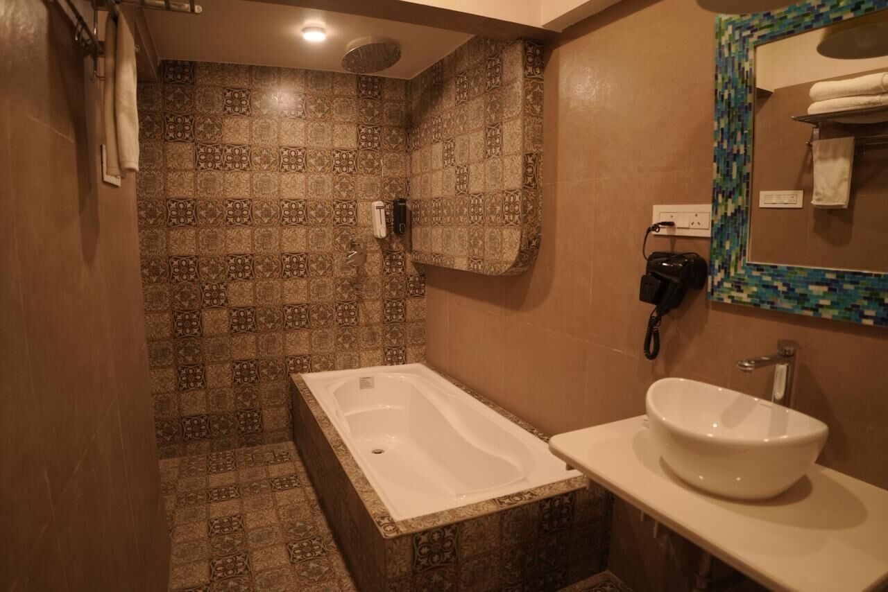 A bathroom with a bathtub, a sink, and patterned tiles.