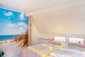 Ein Schlafzimmer mit Meeresblick-Motiv, einem großen Bett mit gestreifter Bettwäsche, einem kleinen Tisch und einem Nachttisch.