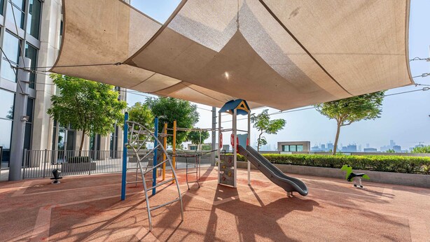Un espace de jeux extérieur comprenant des structures d’escalade, un toboggan et une zone abritée.