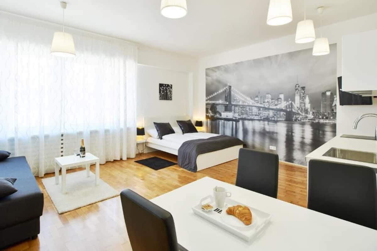 Una camera d'albergo moderna con un letto, un'area pranzo e una cucina.