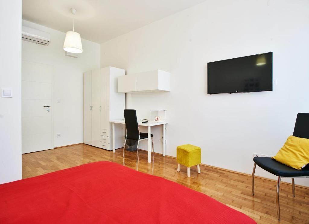A bedroom with a bed, a desk, a chair, a TV, and a wardrobe.