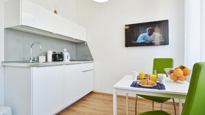 Eine moderne Küche mit weißen Schränken, einem eingebauten Herd und einer Essecke mit gedecktem Tisch für das Frühstück.