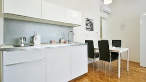 Eine moderne Küche mit weißen Schränken, einem Spülbecken und einem Essbereich mit einem weißen Tisch und schwarzen Stühlen.