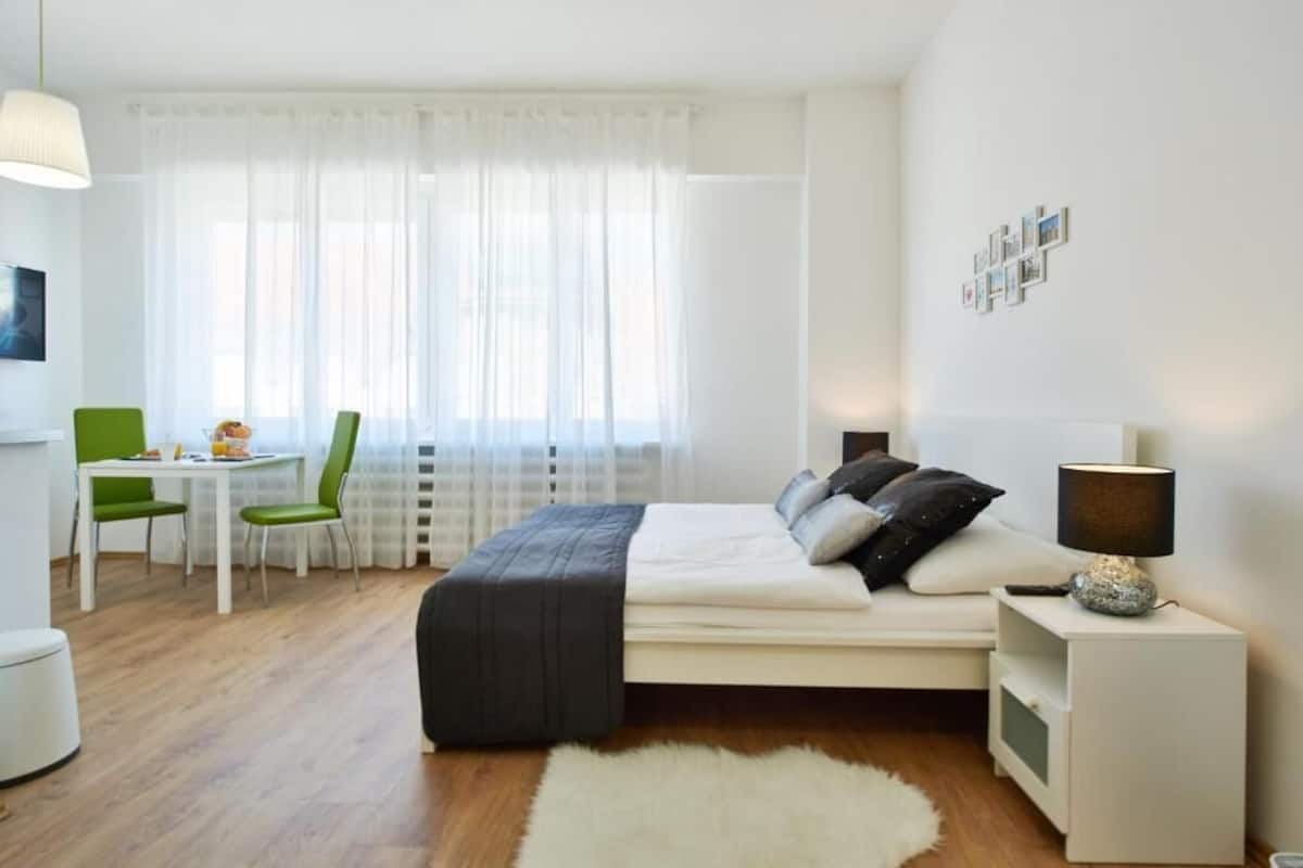 Una camera da letto con un letto, un comodino, una lampada e un'area pranzo con sedie e tavolo.
