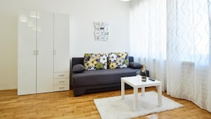 Ein modernes Wohnzimmer mit einem grauen Sofa, einem weißen Couchtisch und einem weißen Kleiderschrank.