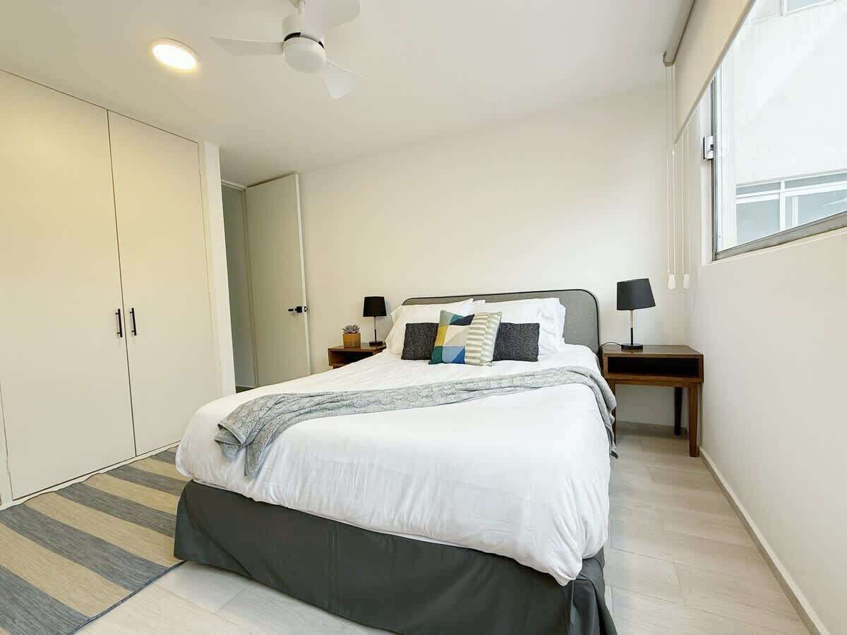 A bedroom with a bed, bedside tables, a wardrobe, and a ceiling fan.