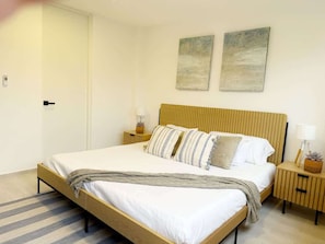 A neatly arranged bedroom with a bed, bedside tables, and wall art.