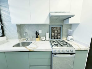 A kitchen with a gas stove, sink, and a coffee menu sign.