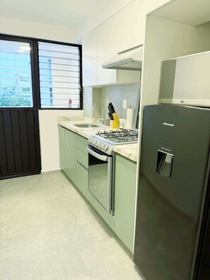 A modern kitchen with a gas stove, sink, and a water dispenser. - Departamento en Condesa (Mexico City)