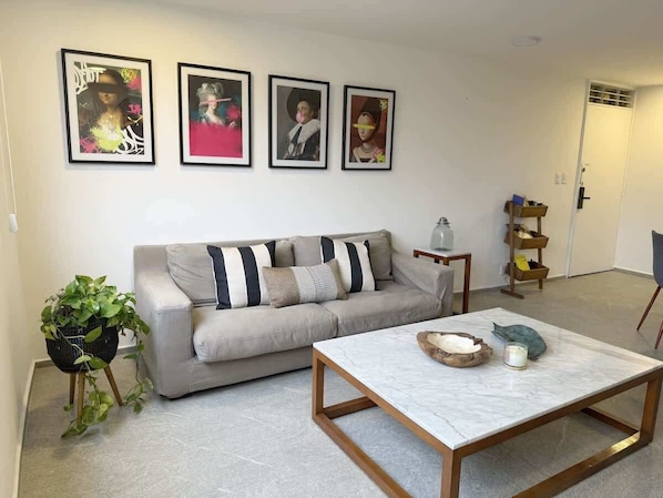 A living room with a sofa, a coffee table, and framed artwork on the wall.