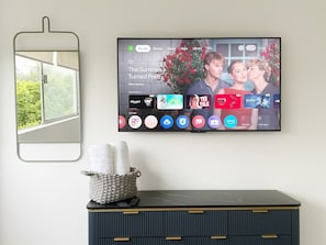 A flat-screen TV mounted on a wall displaying a movie selection menu.