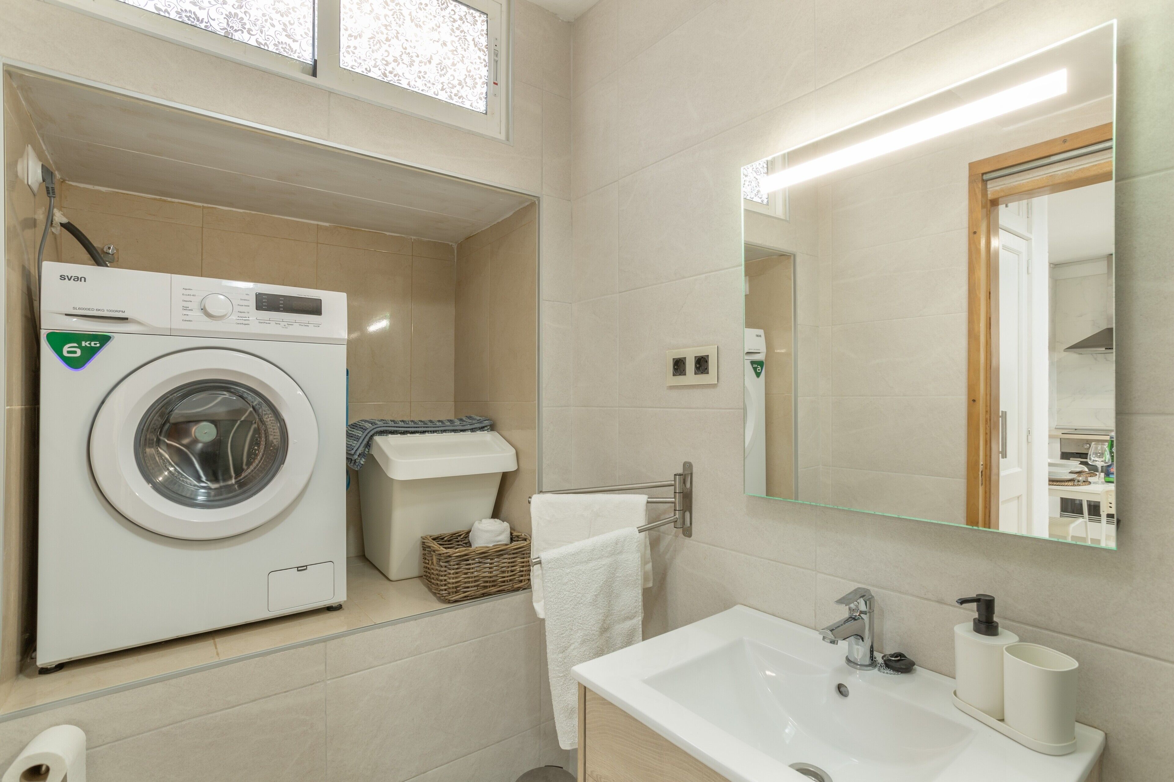 Un baño moderno con lavadora, lavamanos y espejo.
