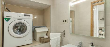 Un baño moderno con lavadora, lavamanos y espejo.