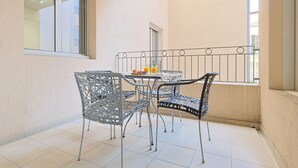 A balcony with a table and chairs, a window, and a railing. - Le Suquet - 2 bedroom - terrace (Cannes)