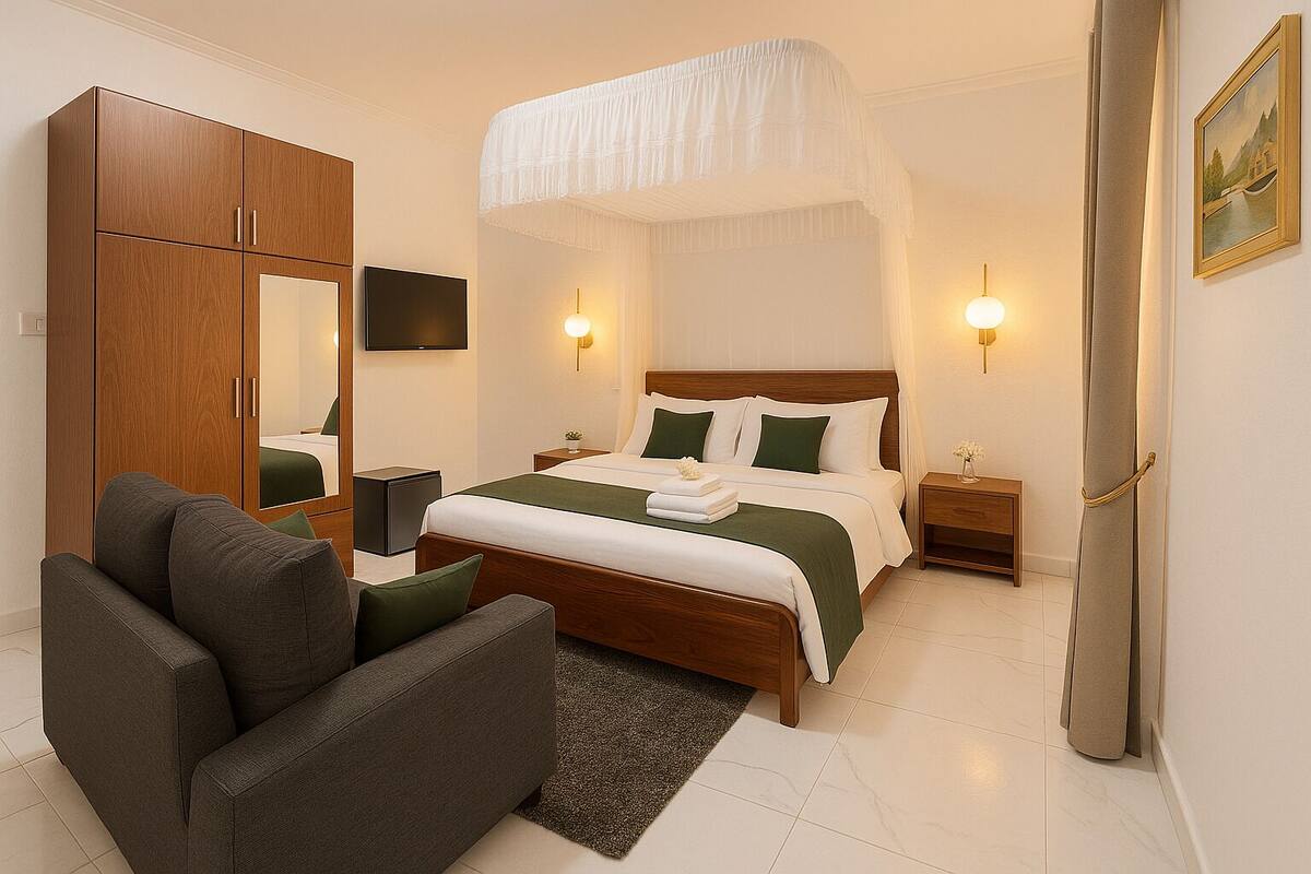 A hotel room with a bed, a sofa, a wardrobe, a TV, and two bedside lamps.