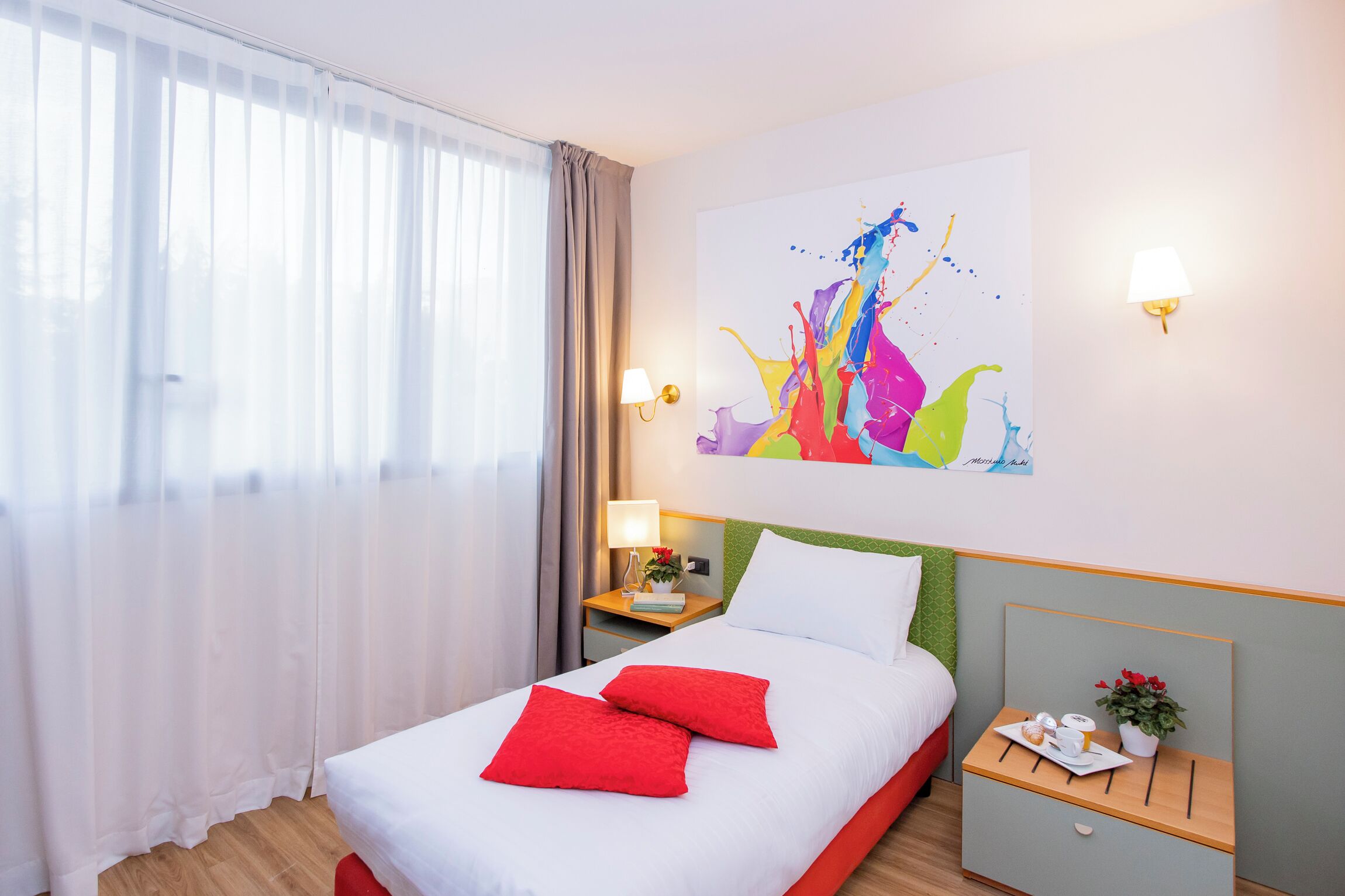 A hotel room with a bed, a nightstand, a lamp, a painting, and a window with curtains.