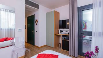 Una camera d'albergo con un letto, una scrivania con un computer, una sedia e un armadio.