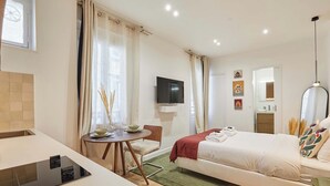 A modern hotel room with a bed, a desk with a laptop, a TV, and a dining area with a table and chairs. - Luxury Suite in the Center of Paris (Paris)