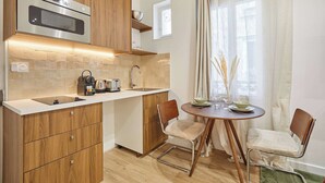 A modern kitchen with wooden cabinets, a built-in oven, and a dining area with two chairs and a table. - Luxury Suite in the Center of Paris (Paris)